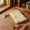 Natural woven Sisal Bag with drawstring and wooden bead on wooden table near window and plant
