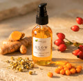 Glow Face Oil bottle with natural ingredients like chamomile, turmeric, and rosehip on a stone surface