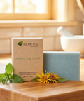 Arnica & Mint - Bar Soap with natural ingredients displayed with mint leaves and yellow flowers on wooden surface