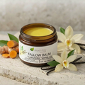 Tallow Balm Moisturizer - Turmeric Vanilla jar with turmeric root and vanilla flowers on a stone surface