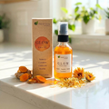 Glow Face Oil bottle with natural ingredients like turmeric and calendula displayed alongside packaging on a sunlit countertop
