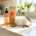 Glow Face Oil with Face & Body Moisturizer Combo with natural ingredients displayed with almonds on a sunlit surface